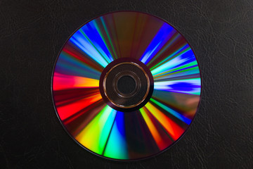 Espectro de colores de luz reflejada por un disco DVD aislado sobre cuero repujado negro