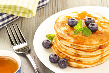 stacked pancakes with fresh blueberries on wooden table