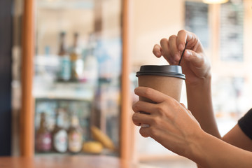 A woman is holding a  coffee cup in coffee's shop at noon