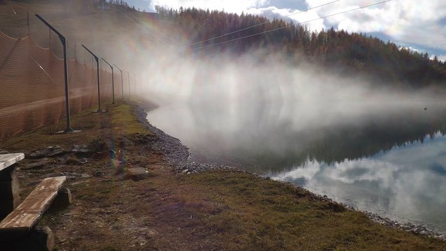View of a reservoir lake for artificial snow, in autumn.  A layer of fog around. Height approx. 1300 m.  In the ski resort Hinterstoder, Upper Austria, Europe.