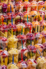 Variety kinds of fresh fruits in plastic cups preparing for smoothie drinks. Colorful fruity drink and beverage.