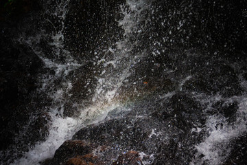 Water falling on stone in the forest black background
