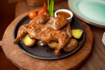 Grilled fried roast Chicken Tabaka and Potato wedges on cutting board on wooden background