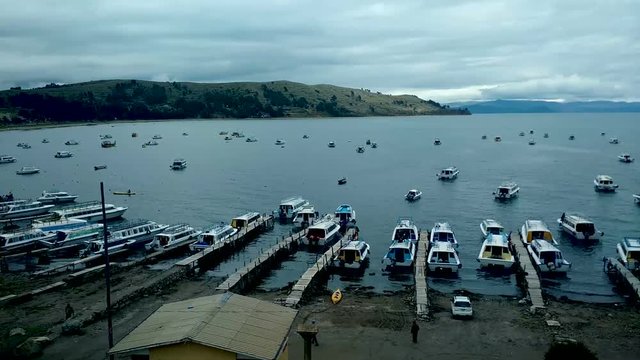Titikaka lake full of boats in Copacabana, Bolivia with a clouded sky and people working