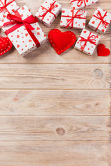 Valentine or other holiday handmade present in paper with red hearts and gifts box in holiday wrapper. Present box of gift on orange wooden table top view with copy space, empty space for design