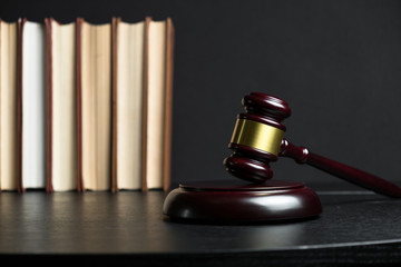 Judge gavel beside pile of books on wooden background