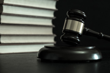 Judge gavel beside pile of books on wooden background