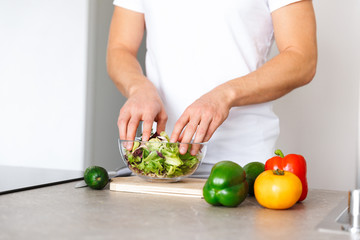 Handsome young man at kitchen at home cooking vegetables make salad.