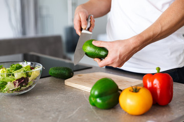 Handsome young man at kitchen at home cooking vegetables make salad.
