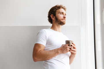 Handsome young man indoors at home drinking coffee.