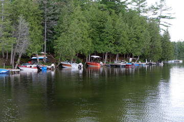 Obraz premium Boats are docked on a piece of land near a treeline just off of a lake.