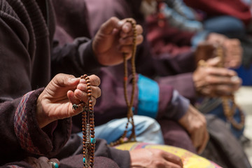 Buddhist beads in the hands of the tibetan pilgrims praying in Lamayuru monastery, Ladakh, India.