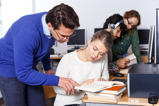 teacher helping female student preparing for exam in computer class