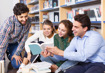 students sitting on floor in library in campus and preparing together for exams