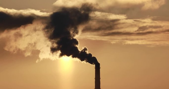 4K video. Steaming cooling towers and smoking industrial stacks against sunset gradient sky