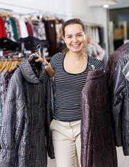 Woman choosing new coat in showroom