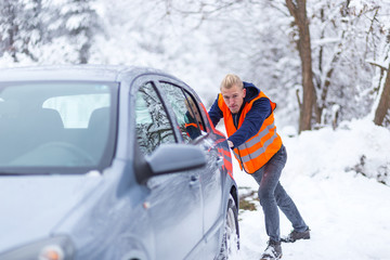 Man pushing car at winter day 