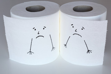 Two white toilet paper rolls sketched with sad faces close to each other, with a melancholic face, representing the sadness feelings