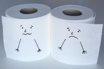 Two white toilet paper rolls sketched with a scared and a melancholic faces, close to each others, representing the fright and the sadness feelings