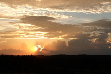 A Wide View Of An Orange / Red Coloured Sunset. The Sun Is Behind The Clouds And Causes A Bright...