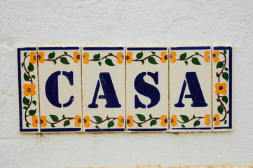 CASA ("Home" or "House" in Spanish, Italian or Portuguese) ceramic tiles vintage sign on the old stone wall. Yellow floral pattern.