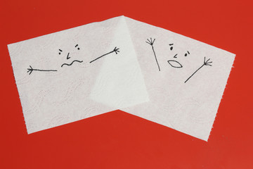 Two white toilet paper pieces sketched with an angry and a shouting face, close to each others, representing the rage and the panic feelings