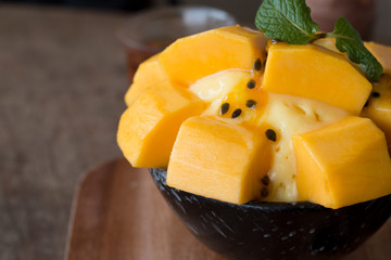Refreshing mango ice cream and passion fruit in ceramic bowl on wooden desk for favorite summer...