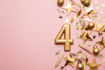 Number 4 gold celebration candle on star and glitter background