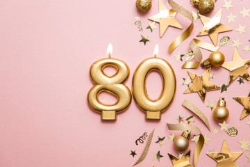 Number 80 gold celebration candle on star and glitter background