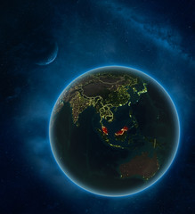 Malaysia at night from space with Moon and Milky Way. Detailed planet Earth with city lights and visible country borders.