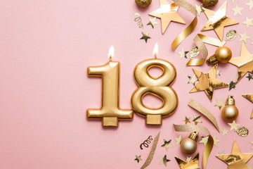 Number 18 gold celebration candle on star and glitter background