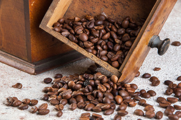Old wooden coffee grinder on concrete background.