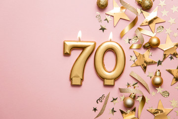 Number 70 gold celebration candle on star and glitter background