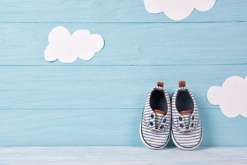 Baby boy shoes on a blue wooden background with clouds