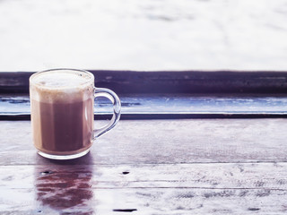 A cappuccino latte coffee in clear glass on wooden table window background