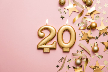 Number 20 gold celebration candle on star and glitter background