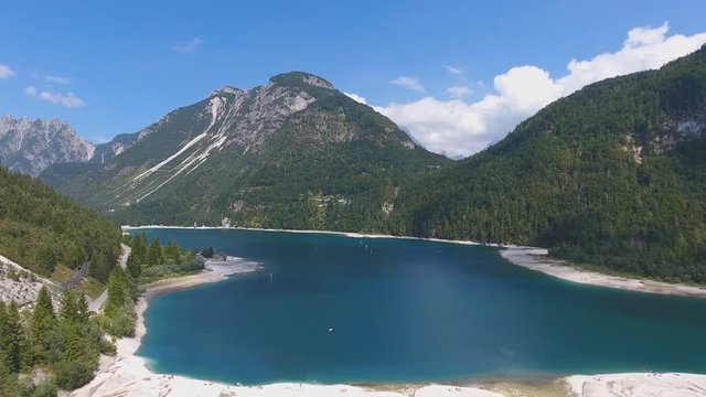 Aerial view of Lake Predil with turquoise water and mountains in background near Tarvisio in European Alps, Italy