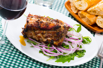 Grilled rack of pork with arugula and onion