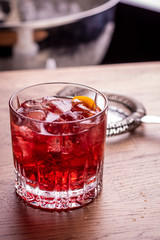 Negroni make with gin, martini red, campari bitter, served in a rock glass and garnished with orange peel