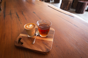 Piccolo Latte art in small glass with hot tea on wooden desk