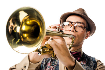 Obraz premium close up portrait of young mixed race man in stylish hat and eyeglasses playing on trumpet isolated on white