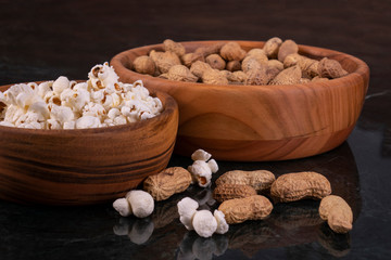 Peanuts with Popcorn in golden wood bowl on black marble table