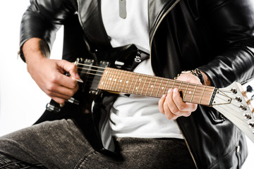 Fototapeta na wymiar partial view of male rock musician in leather jacket playing on electric guitar isolated on white