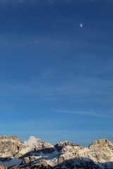 panorama delle dolomiti italiane con cielo nuvole e luna poco prima di sera