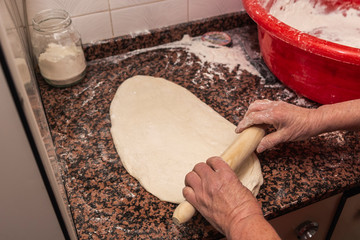 Photograph of how an old woman prepares the dough for a pizza.
