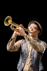 handsome male jazzman in hat and eyeglasses playing on trumpet isolated on black