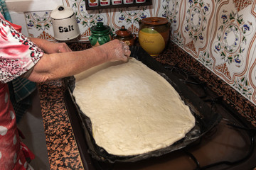 Photograph of how an old woman prepares the dough for a pizza.