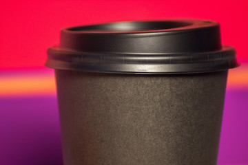 black paper Cup with plastic lid. coffee or takeaway on a violet and pink background. brutal glass