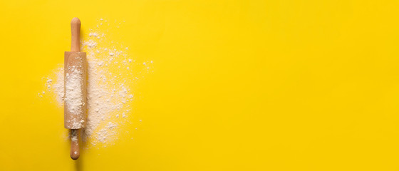 Rolling pin with flour on yellow background. Baking, menu, recipe concept. Top view. Banner with...