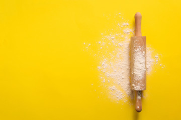 Rolling pin with flour on yellow background. Baking, menu, recipe concept. Top view. Banner with copy space for your text